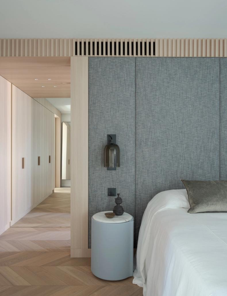 The master bedroom in woven grey panelling, corridor beyond