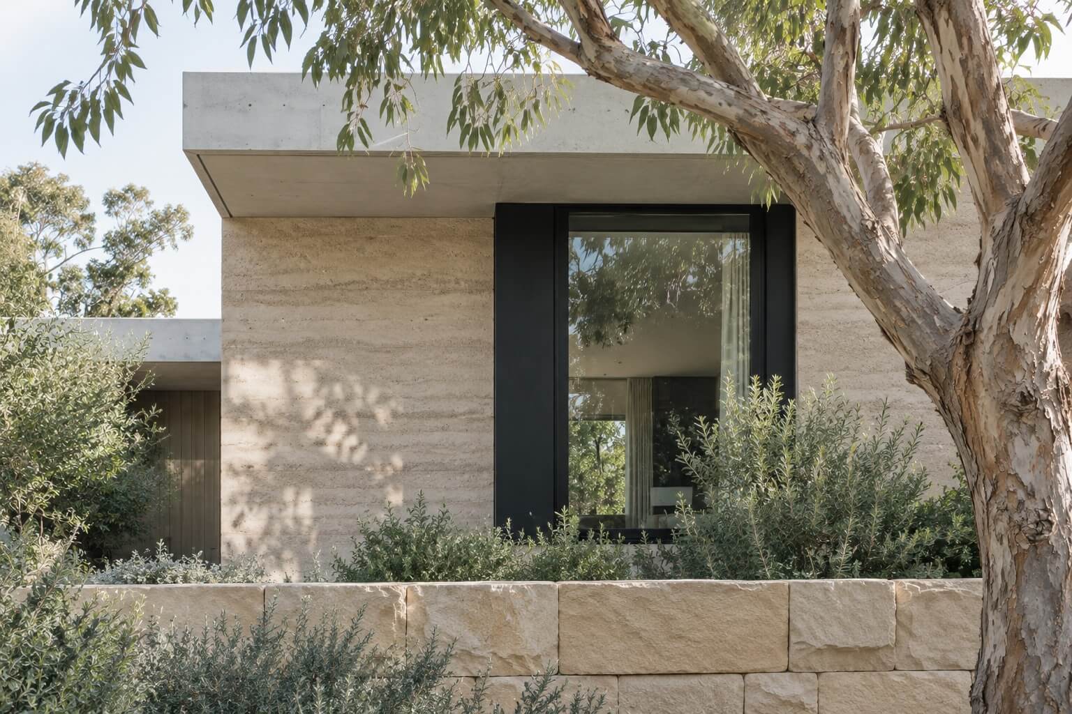 A completed stone and concrete home under the gums