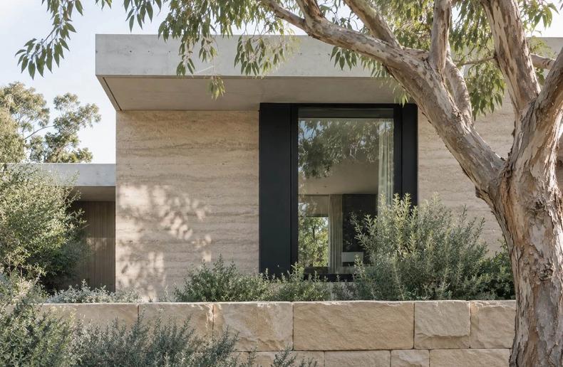 A completed stone and concrete home under the gums