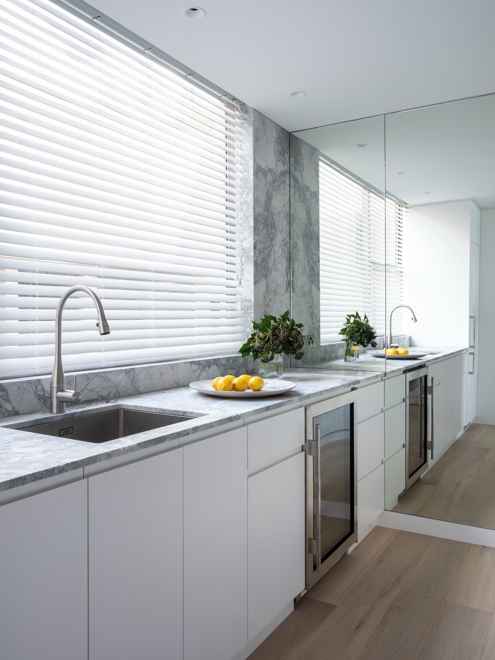 The marble kitchen bench running under custom floor-to-ceiling mirrors