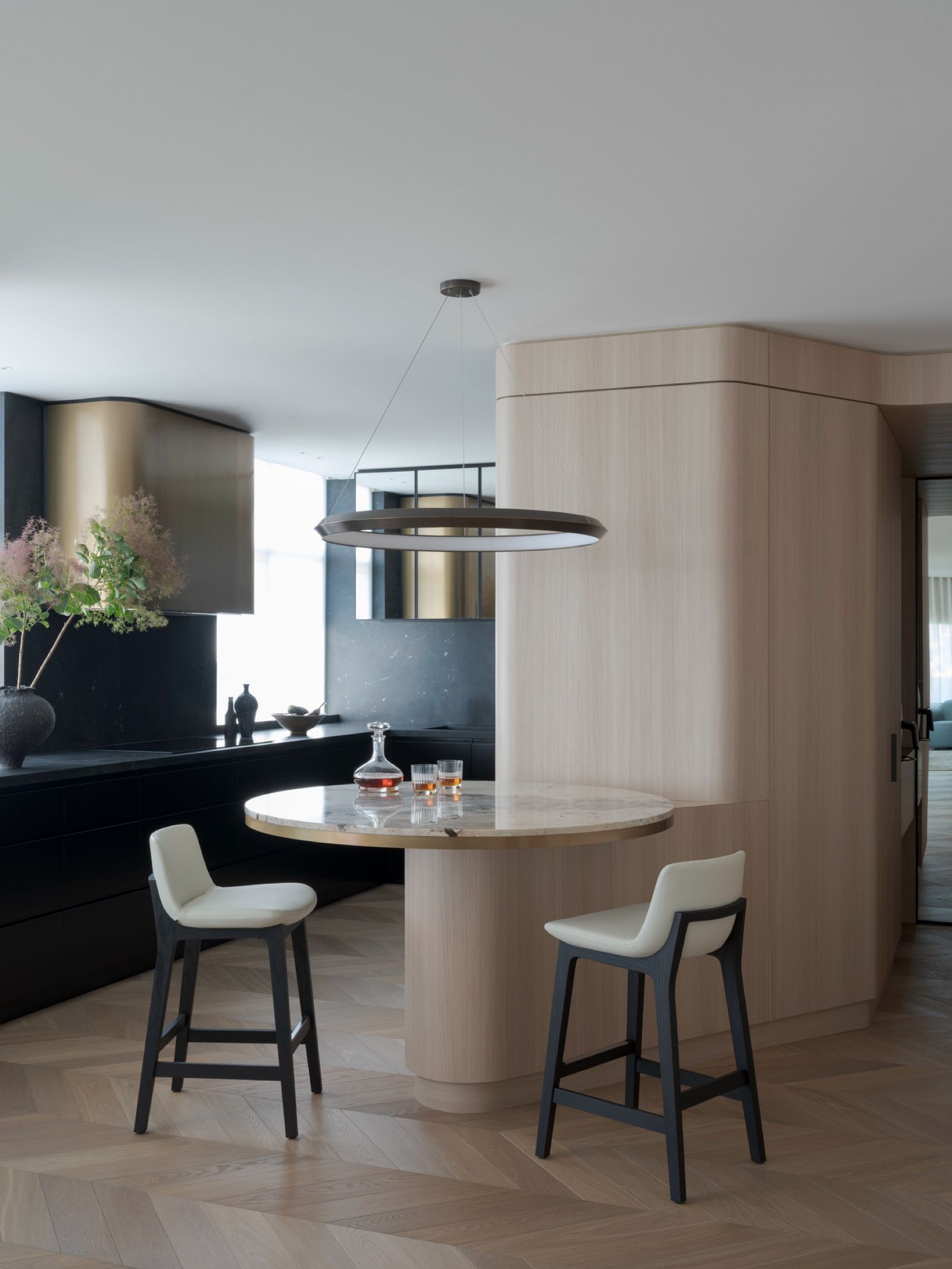 Curved timber-veneer cabinetry beside the round marble table