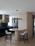 Curved timber-veneer cabinetry beside the round marble table