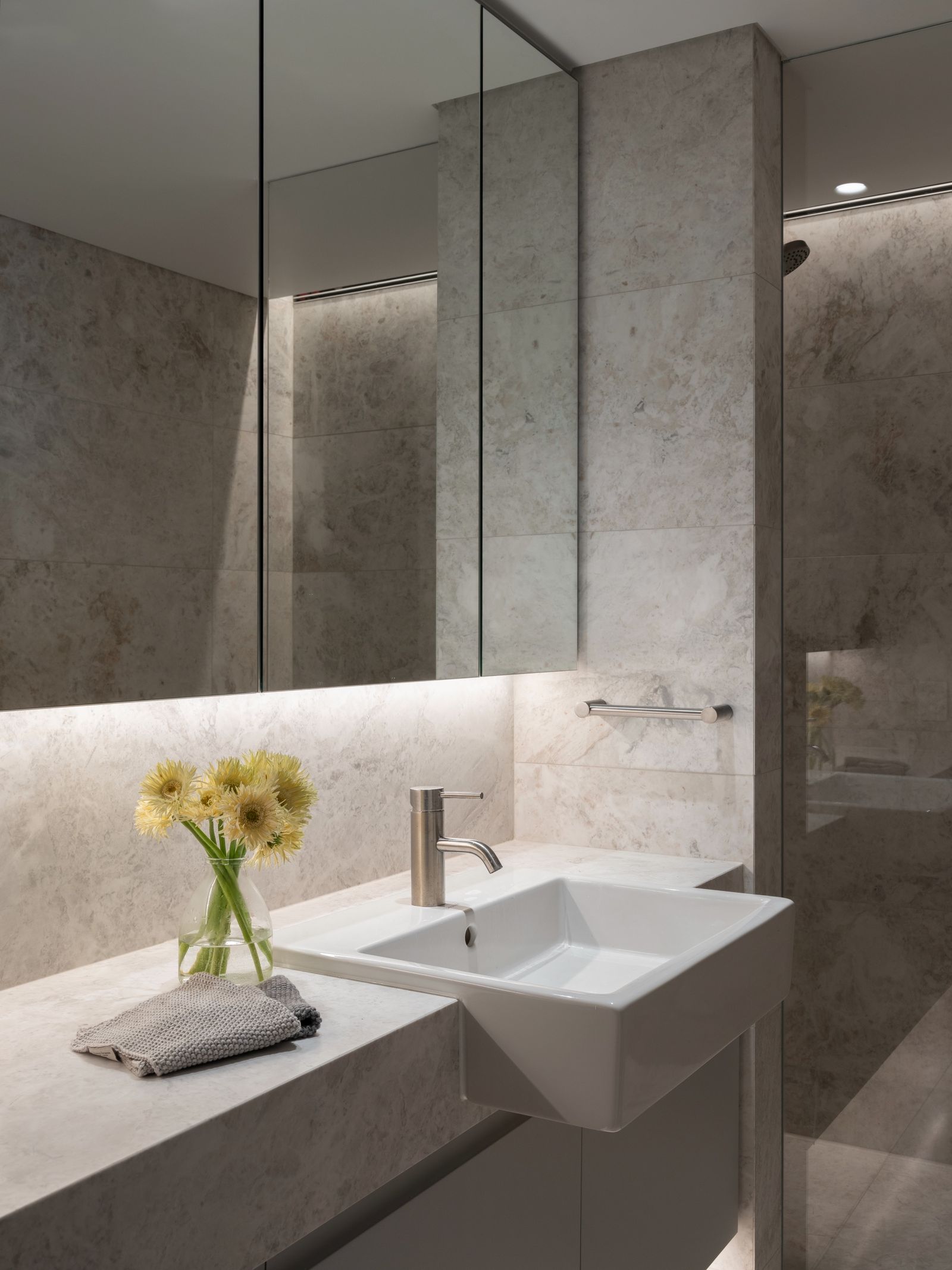 The marble bathroom vanity under full-height mirrored cabinets