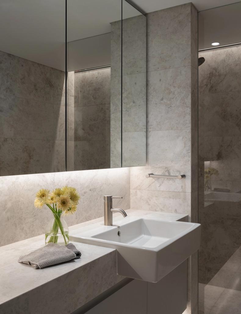 The marble bathroom vanity under full-height mirrored cabinets