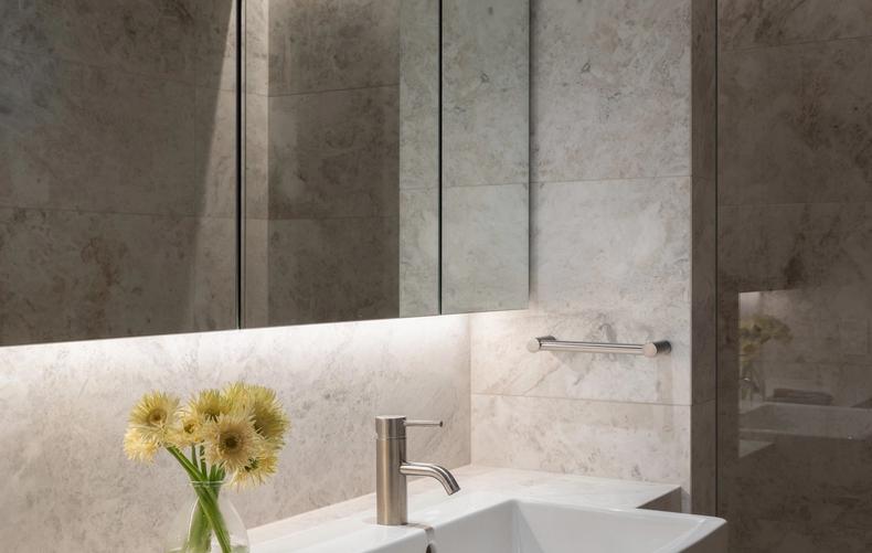 The marble bathroom vanity under full-height mirrored cabinets