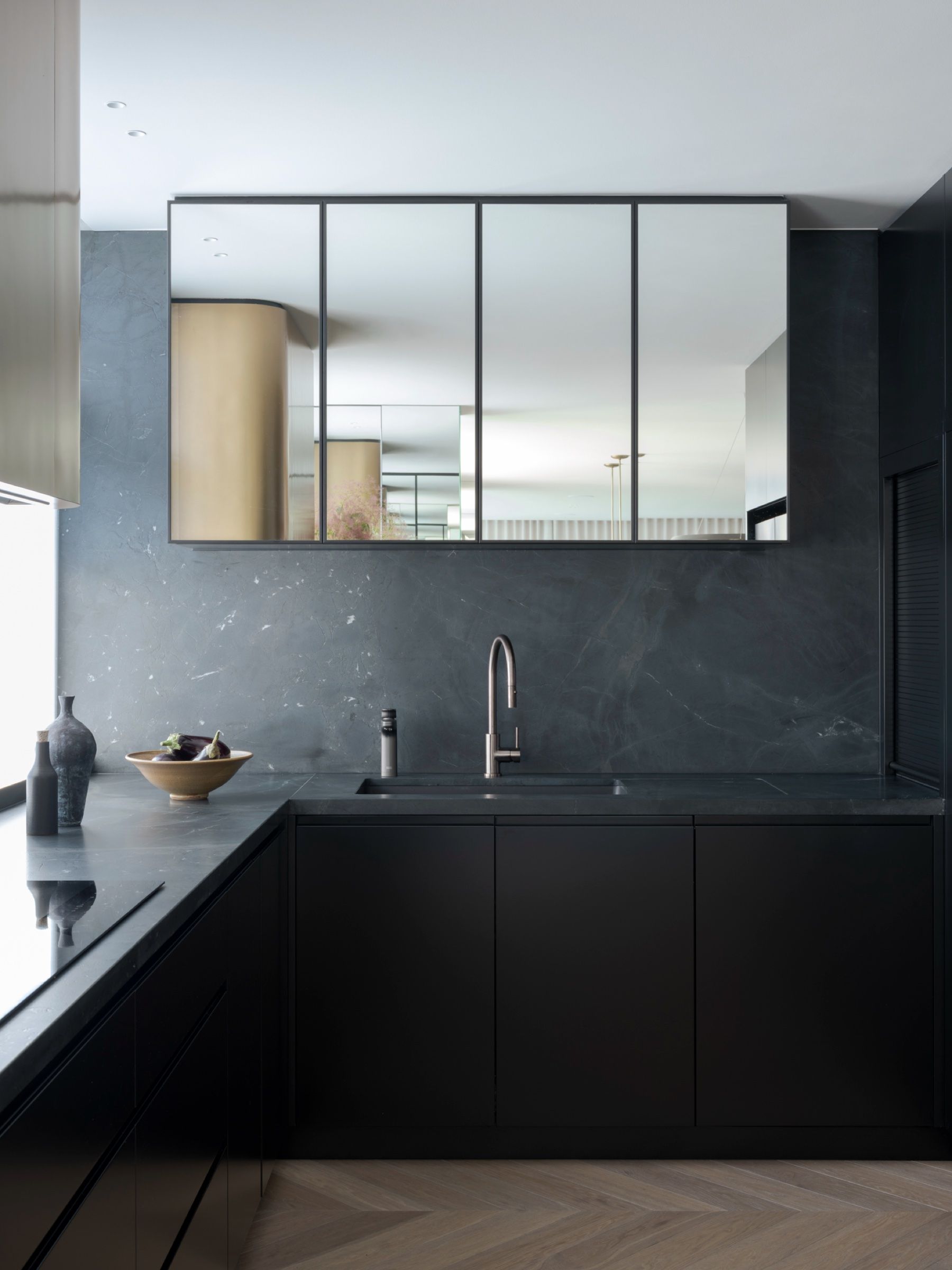 The kitchen in honed dark stone with a mirrored splashback