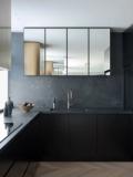 The kitchen in honed dark stone with a mirrored splashback