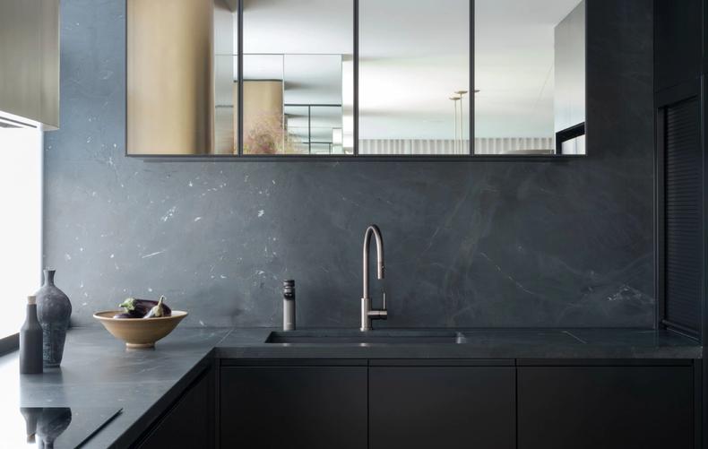 The kitchen in honed dark stone with a mirrored splashback
