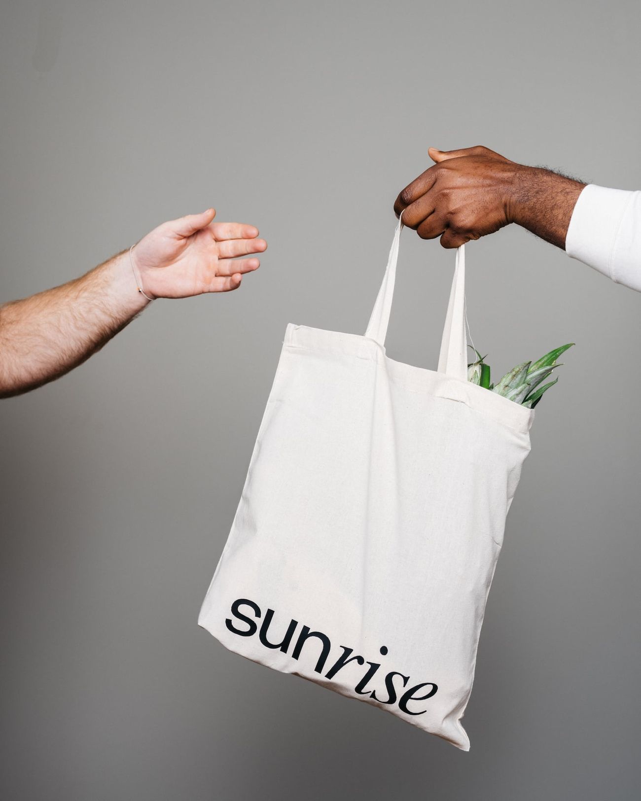 A Sunrise grocery bag handed from one person to another