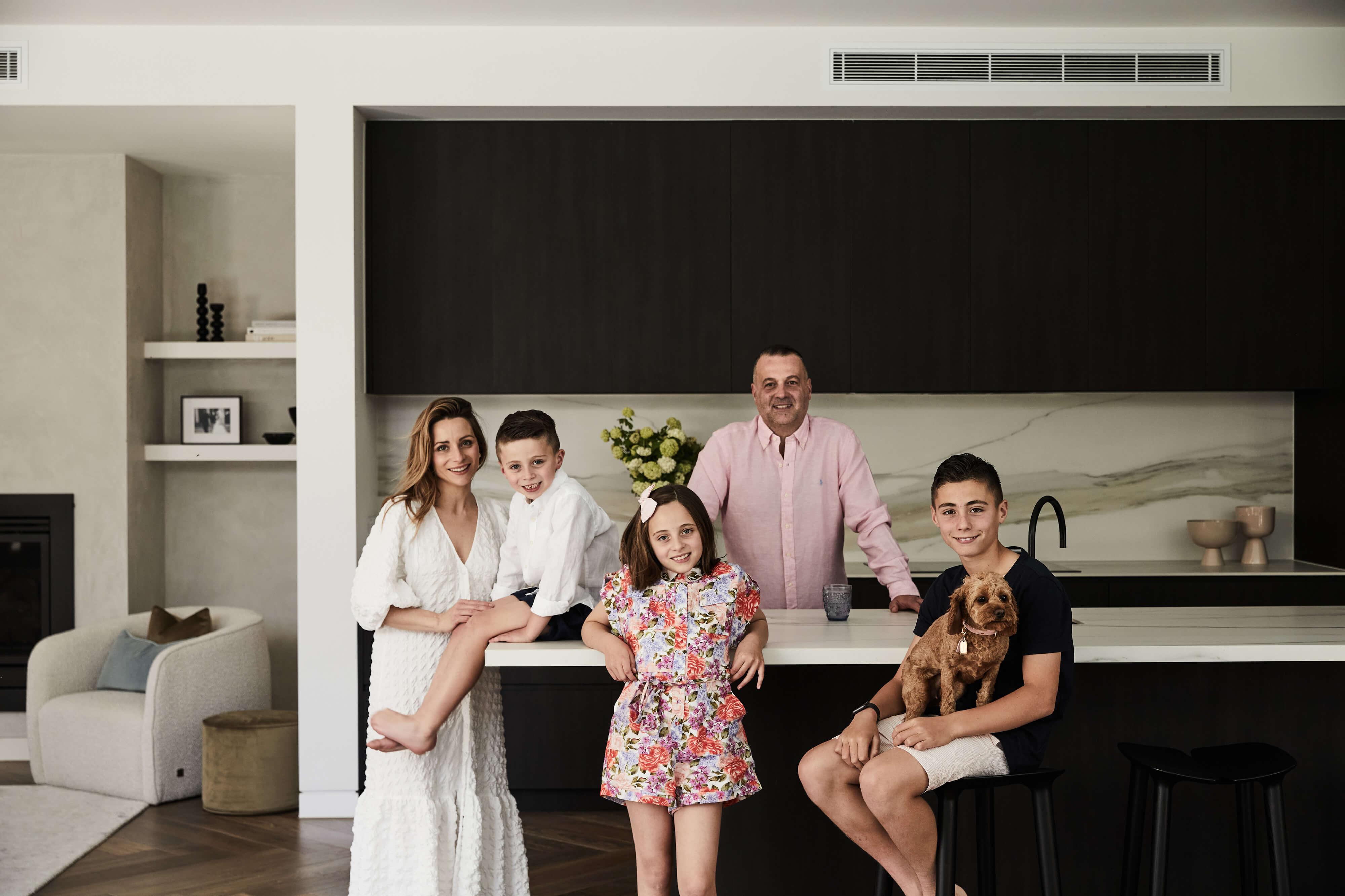 A modern kitchen scene with a happy family posing for a photograph