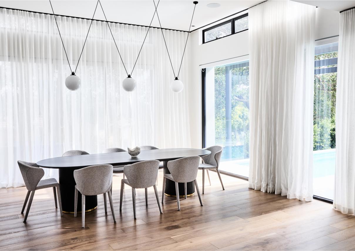 A spacious dining space with feature pendants and large floor to ceiling windows