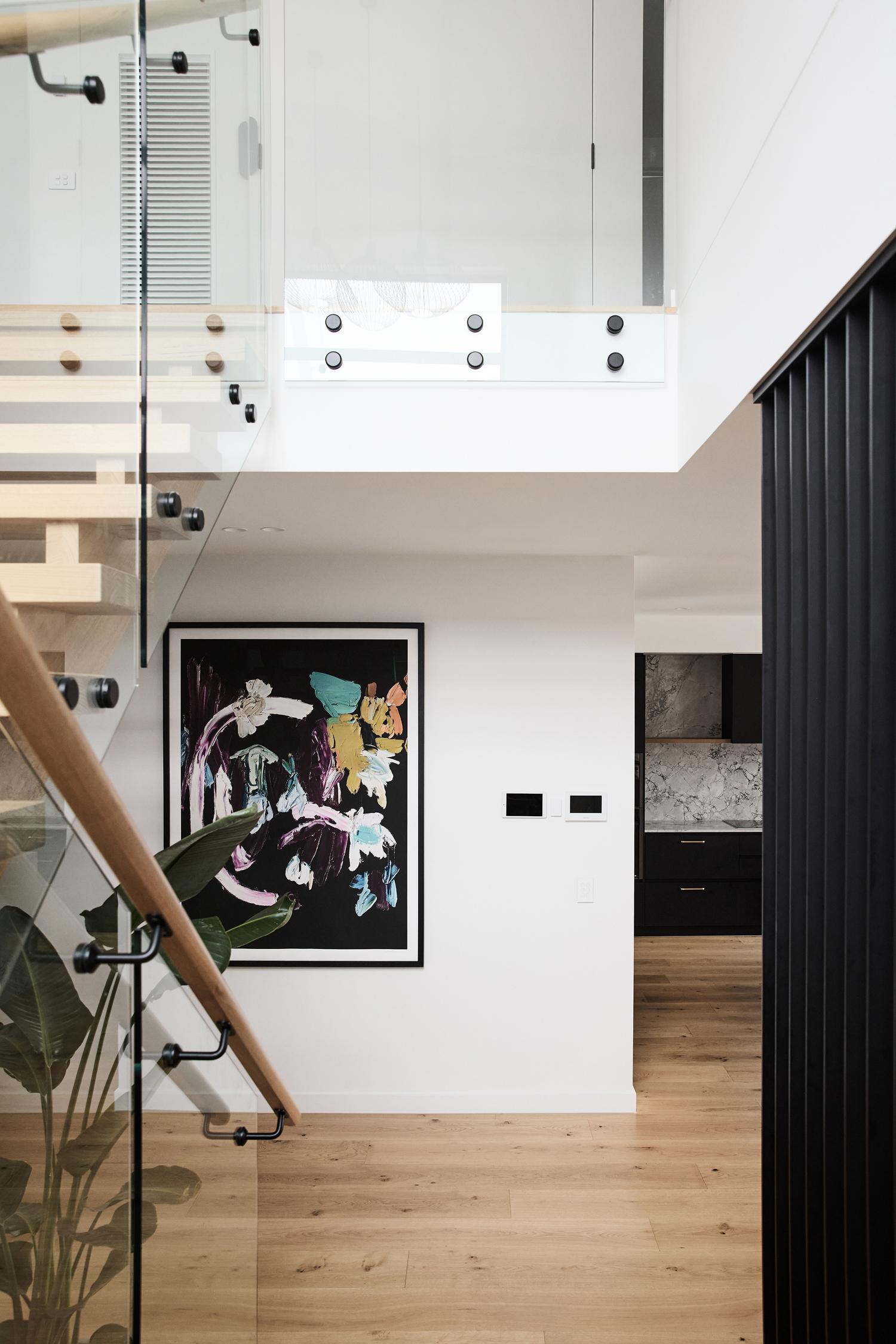 A contemporary hallway and stair void with warm timber flooring throughout designed and built by Thomas Archer