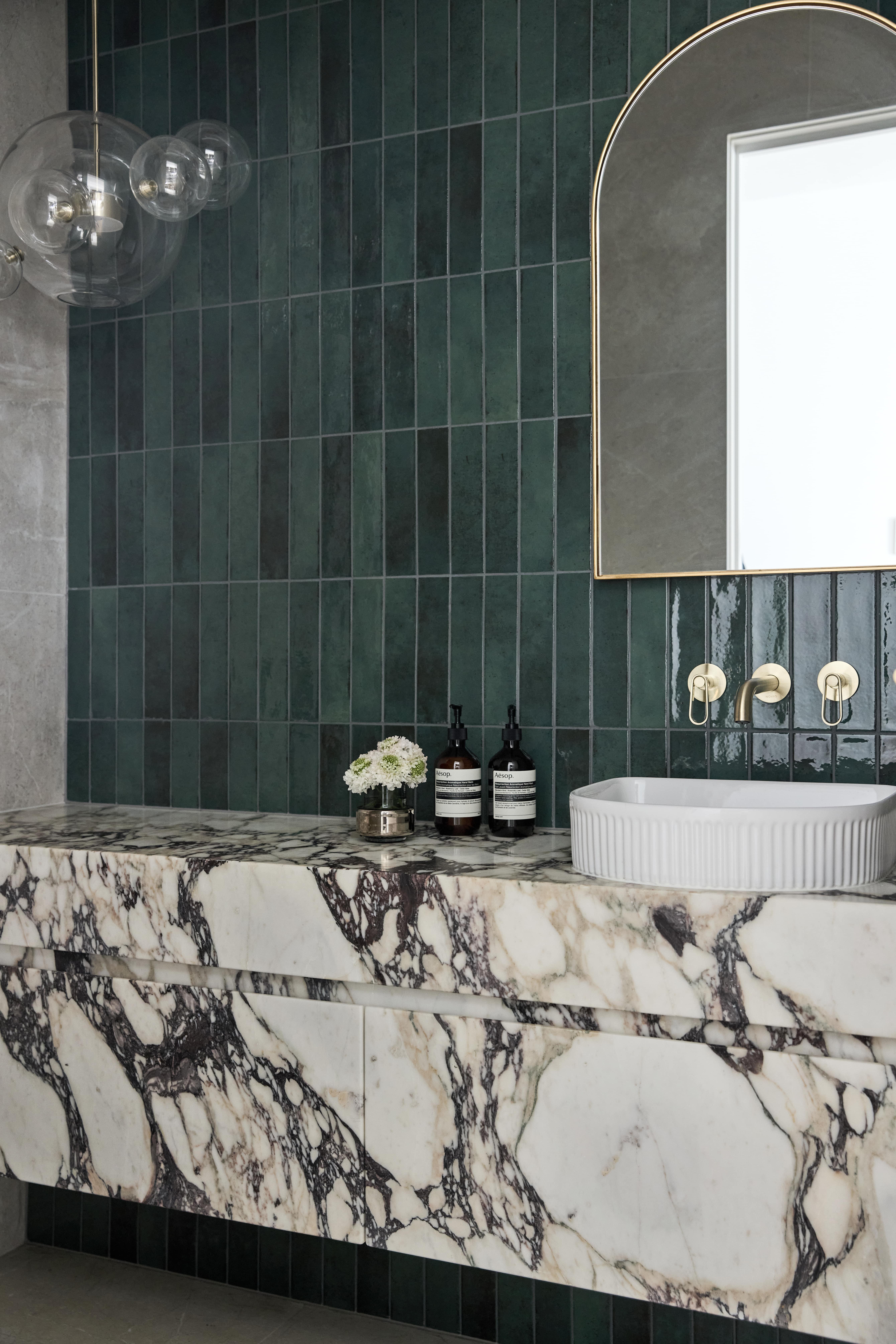 Striking powder room with moody dark green mosaic tiles and a Calacatta Viola basin, designed and built by Thomas Archer.