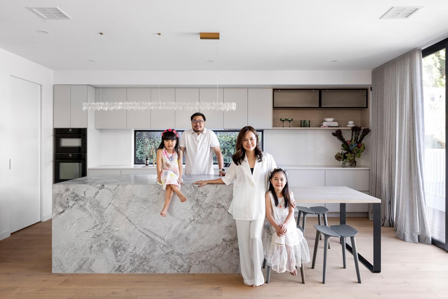 Family standing around their kitchen bench of their Thomas Archer architecturally designed home