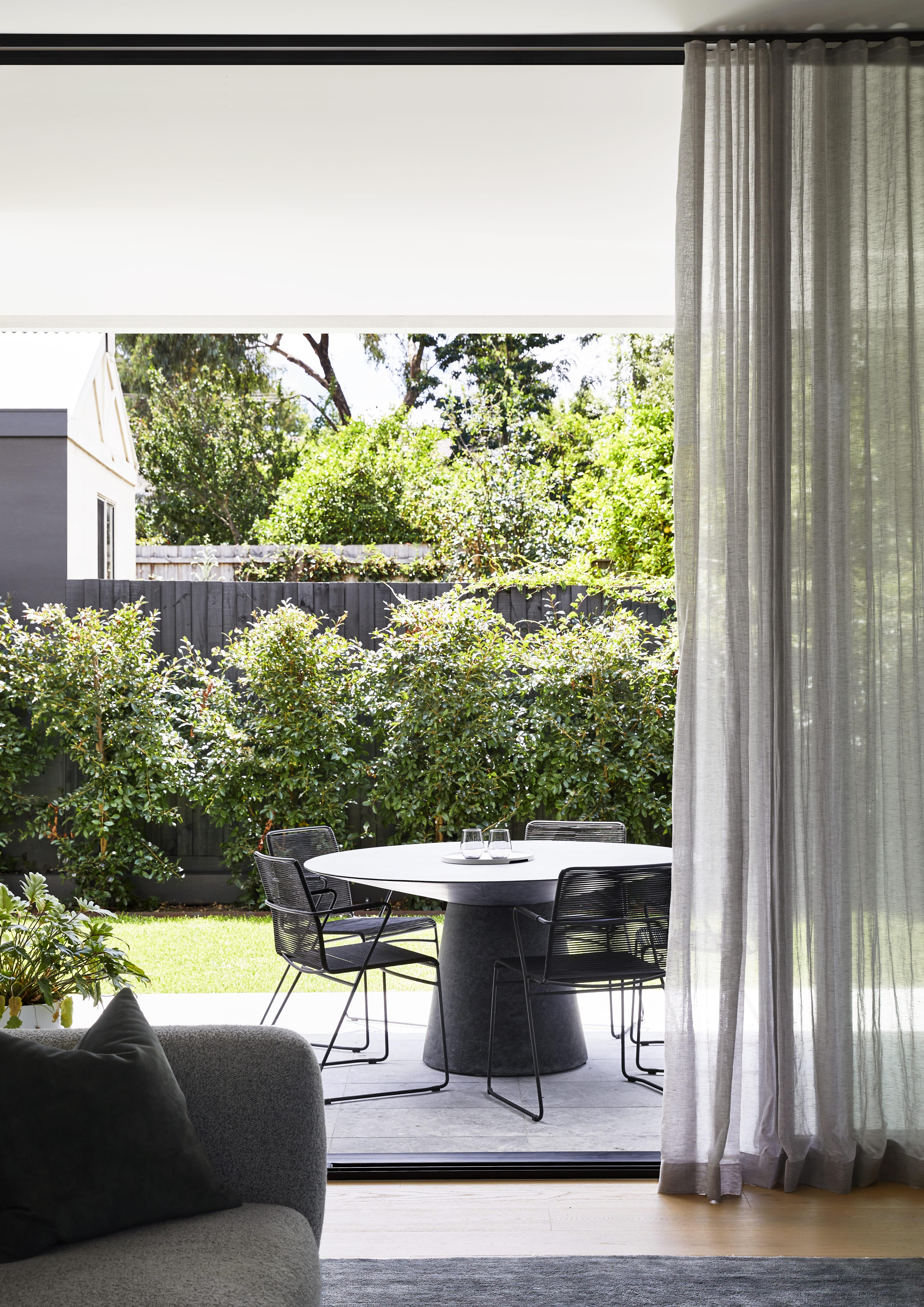 A living room with a table and chairs placed in front of a sliding glass door.