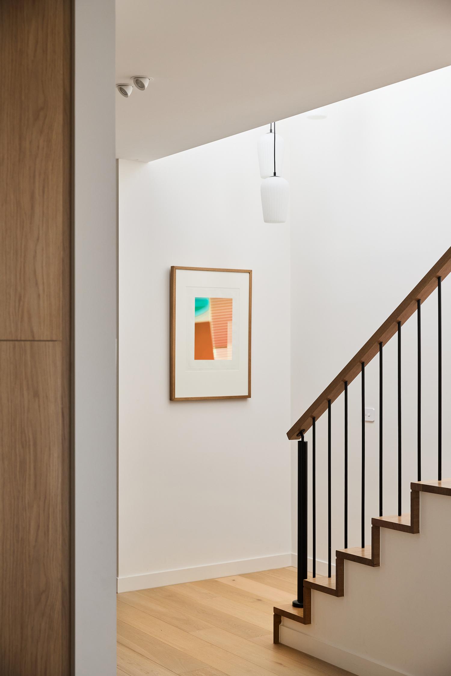 A contemporary hallway and stair void with warm timber flooring throughout designed and built by Thomas Archer