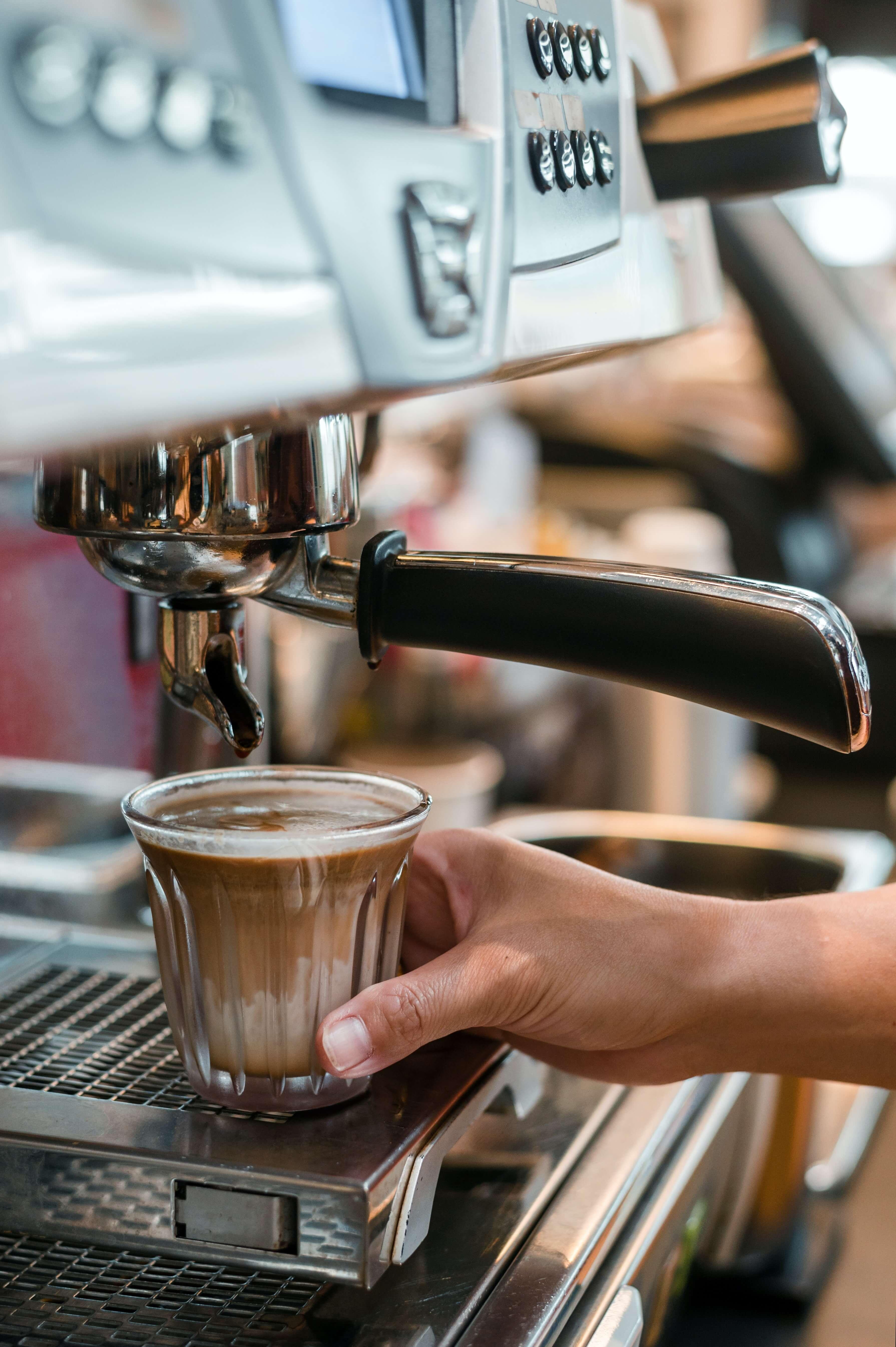 A person operating an espresso machine to brew coffee.