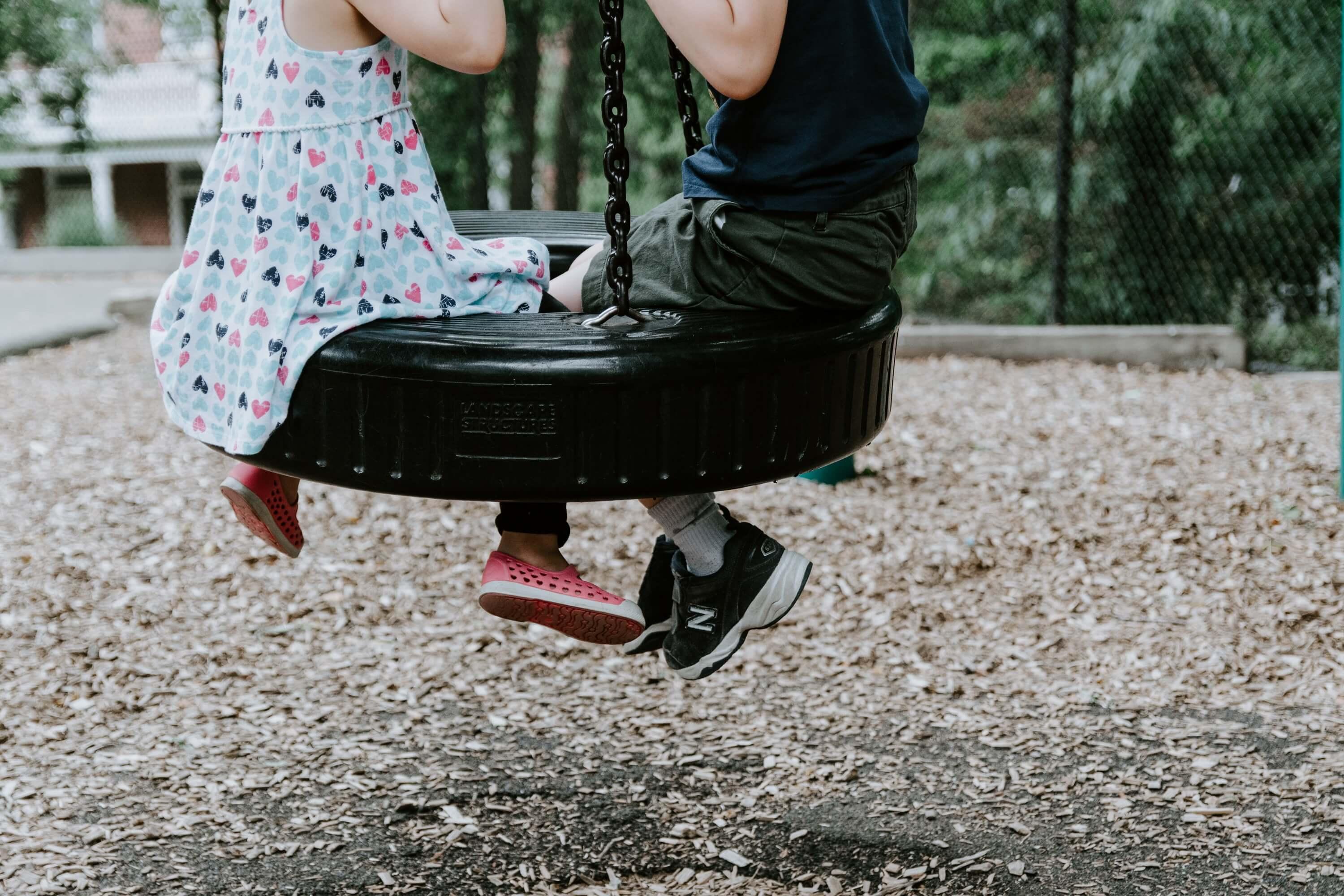 Two children on a swing at a playground