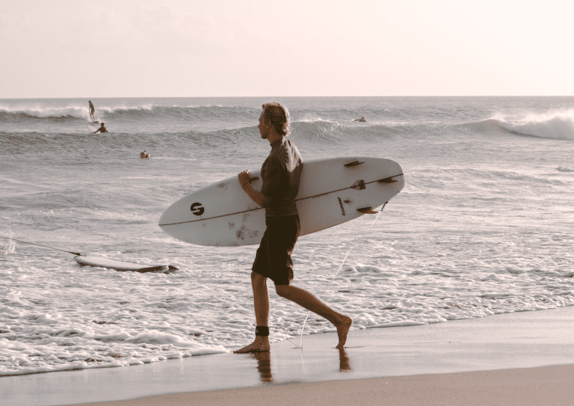 Surfer walking into the water with surfboard