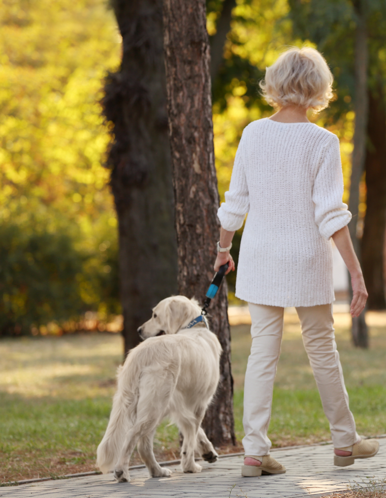 women walking dog thorugh park