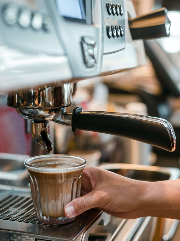 A person operating an espresso machine to brew coffee.