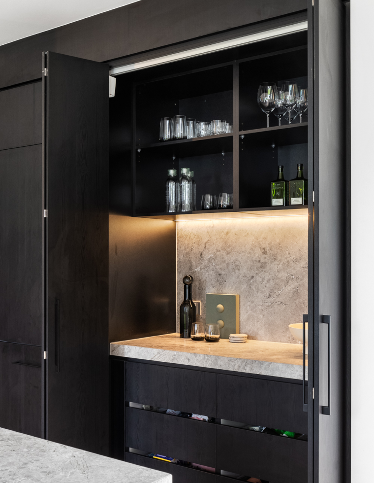 A modern in built bar with sleek black cabinets and a luxurious marble counter.