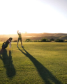 A golfer playing on a picturesque course as the sun sets in the background.
