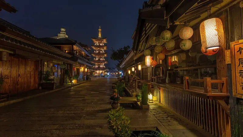 Traditional wooden buildings and illuminated lanterns along a street in Kyoto at dusk