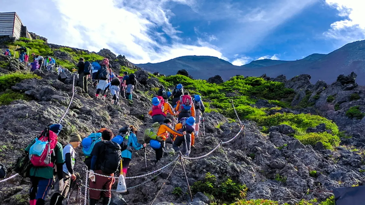 Hikers ascending a rocky trail on Mount Fuji