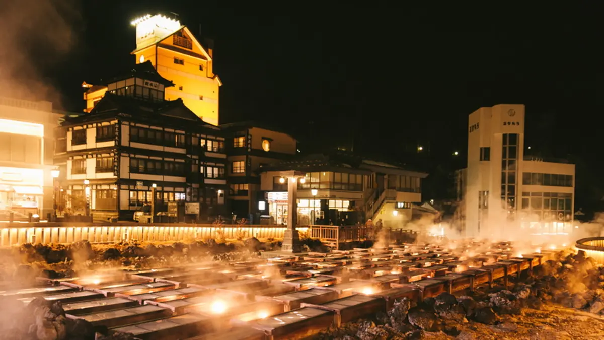 Steam rising from the illuminated Yubatake hot spring field at night in Kusatsu Onsen, Gunma