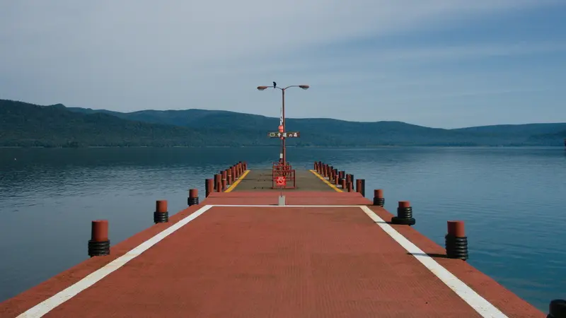 A red pier extending into Lake Akan with hills in the background