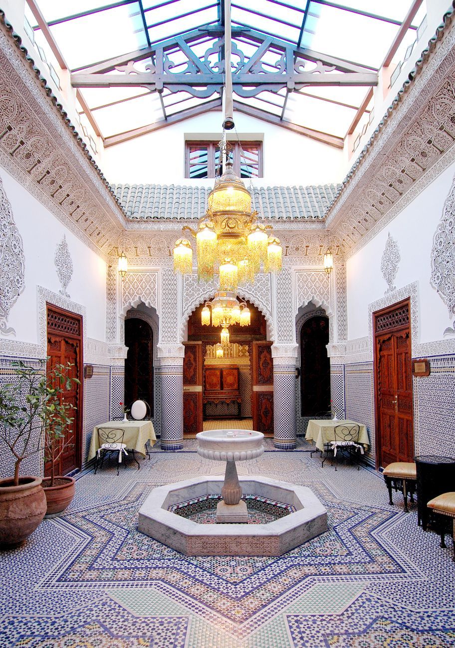 Elegant Moroccan courtyard interior with intricate design and luxurious chandelier.