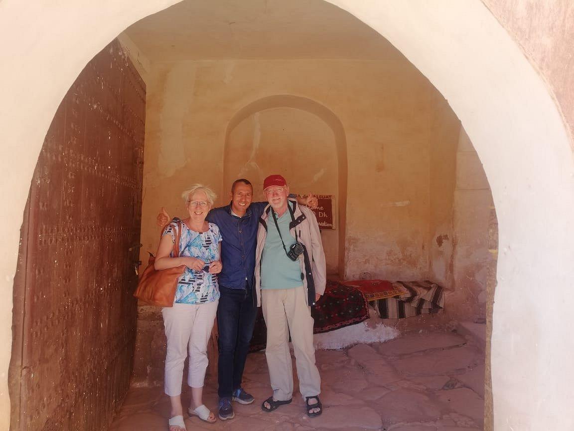 Two guests with their AZA Morocco Tours guide in the arched gateway of an old kasbah