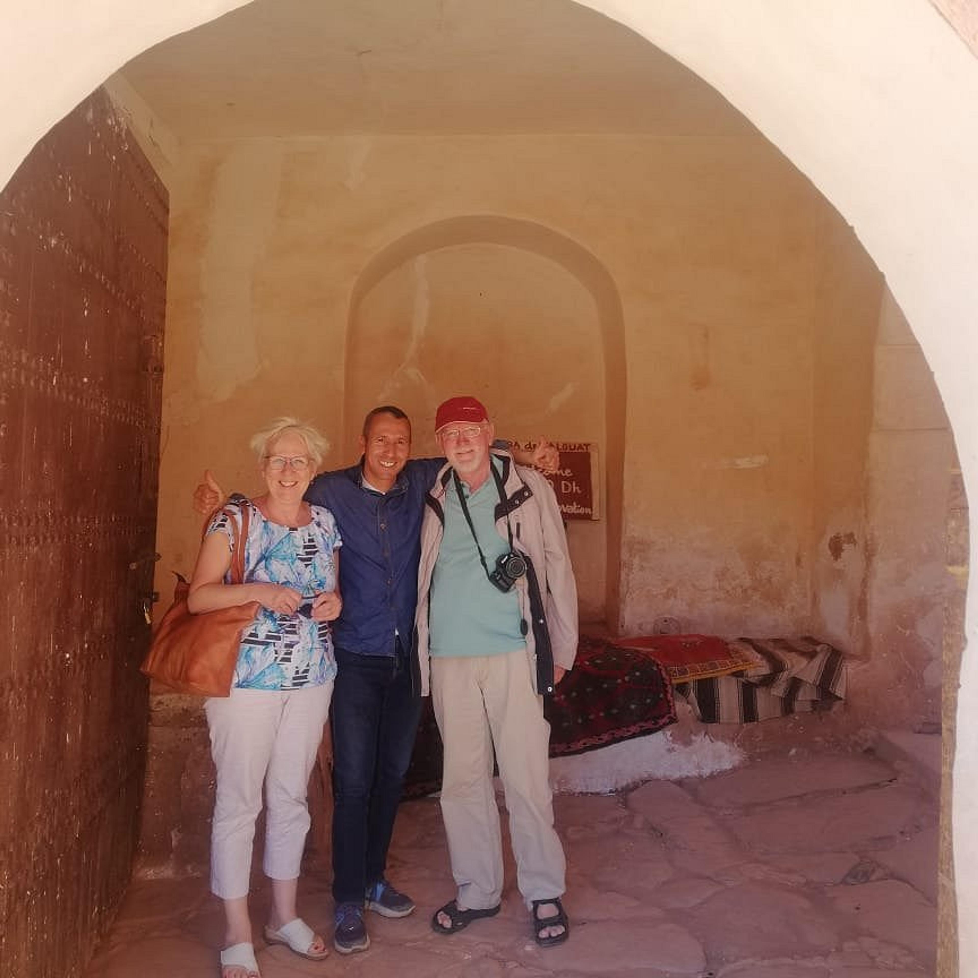 Two guests with their AZA Morocco Tours guide in the arched gateway of an old kasbah
