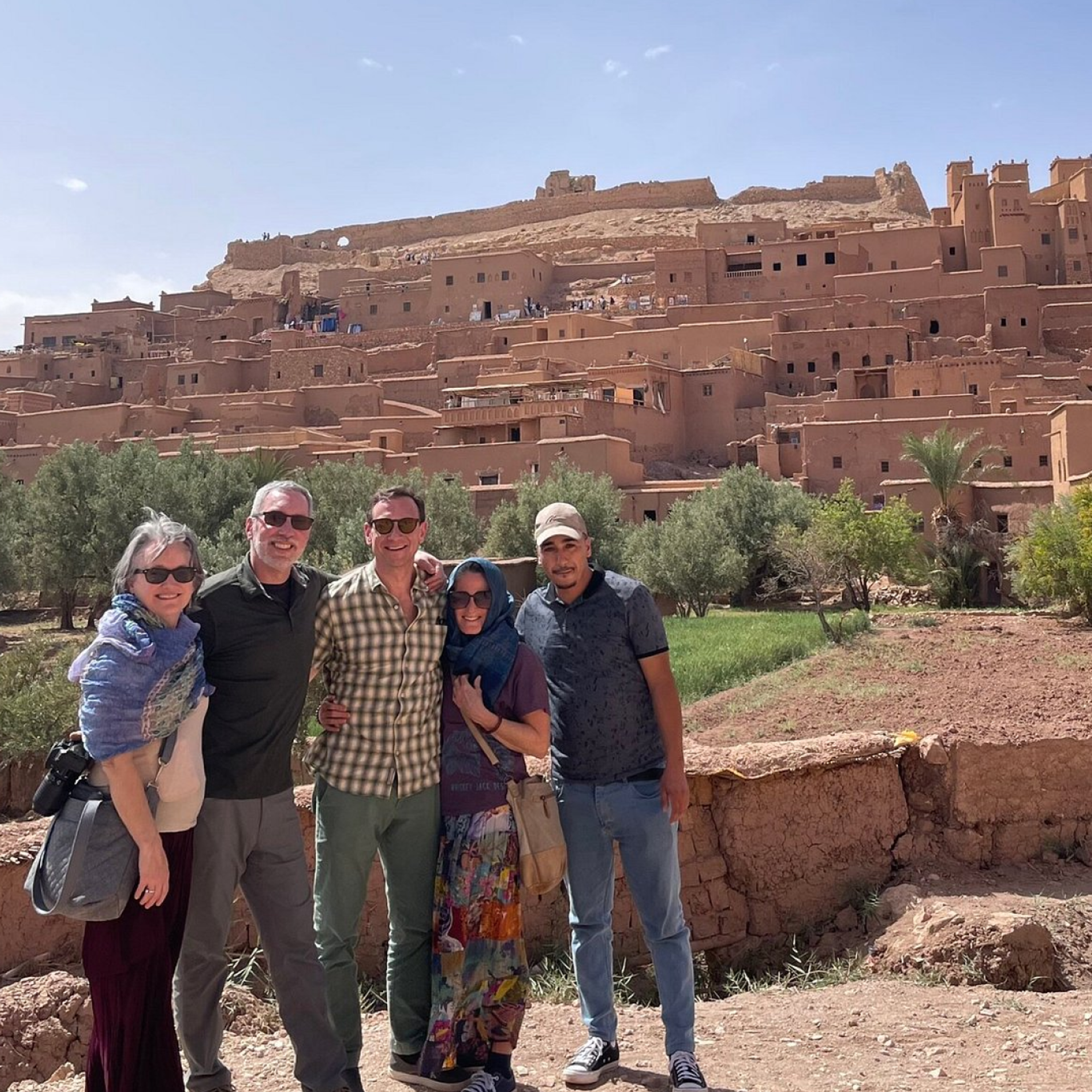 Four guests with their AZA Morocco Tours guide in front of the Aït Benhaddou kasbah