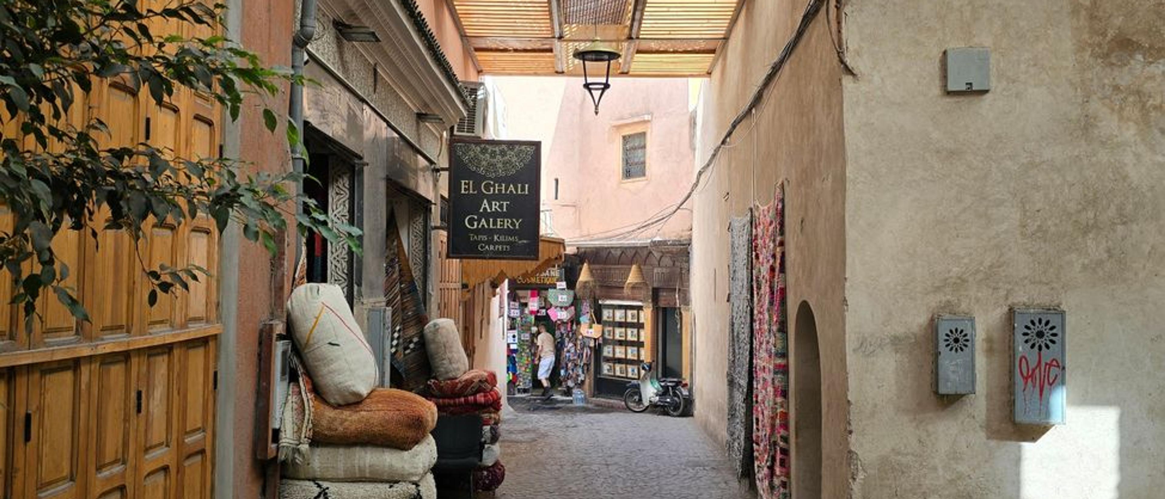 Explore a serene alleyway in the Marrakech Medina filled with rugs and cultural artistry.