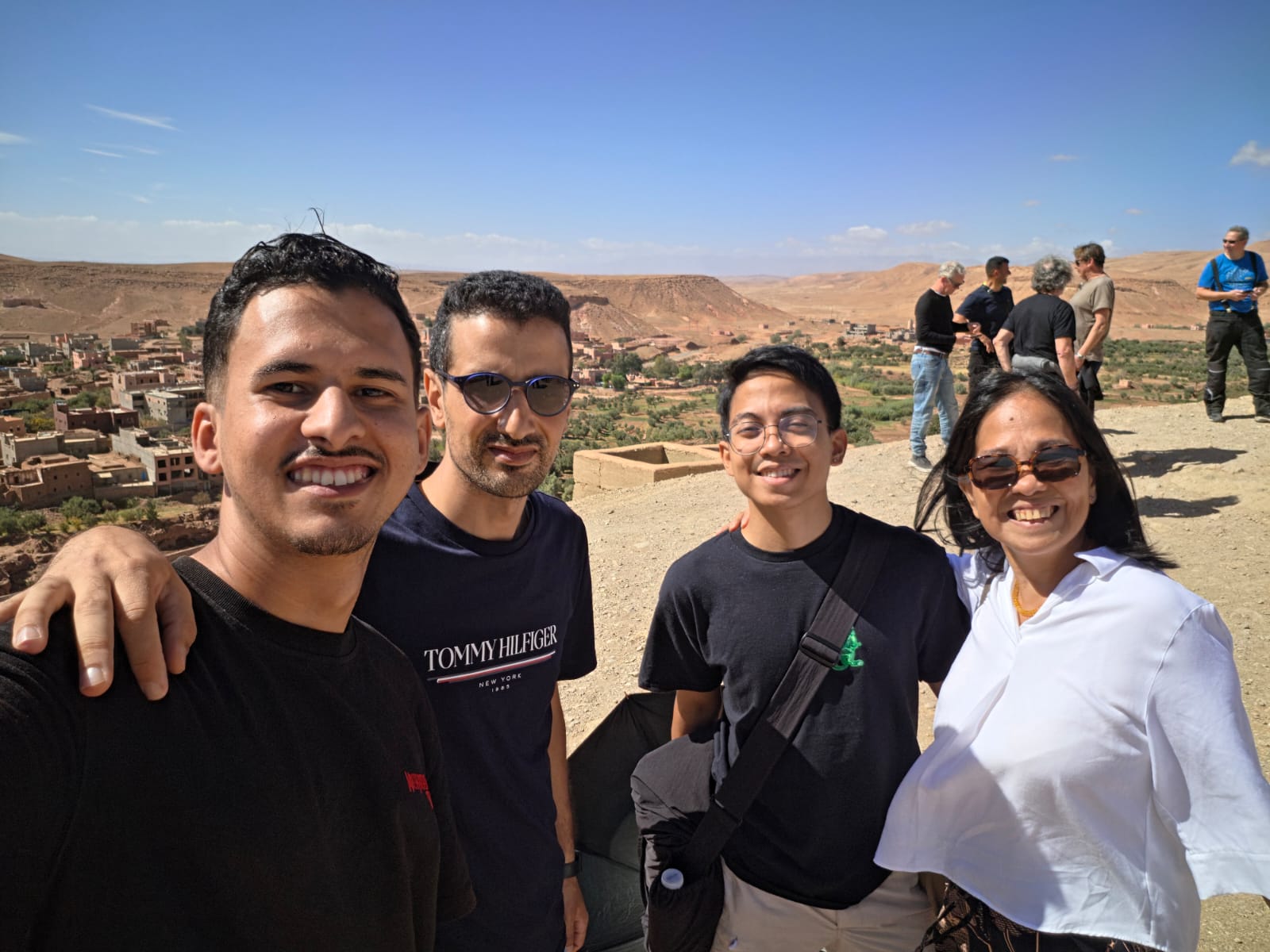 Moha and a colleague from AZA Morocco Tours with two guests at a viewpoint over a desert valley in southern Morocco