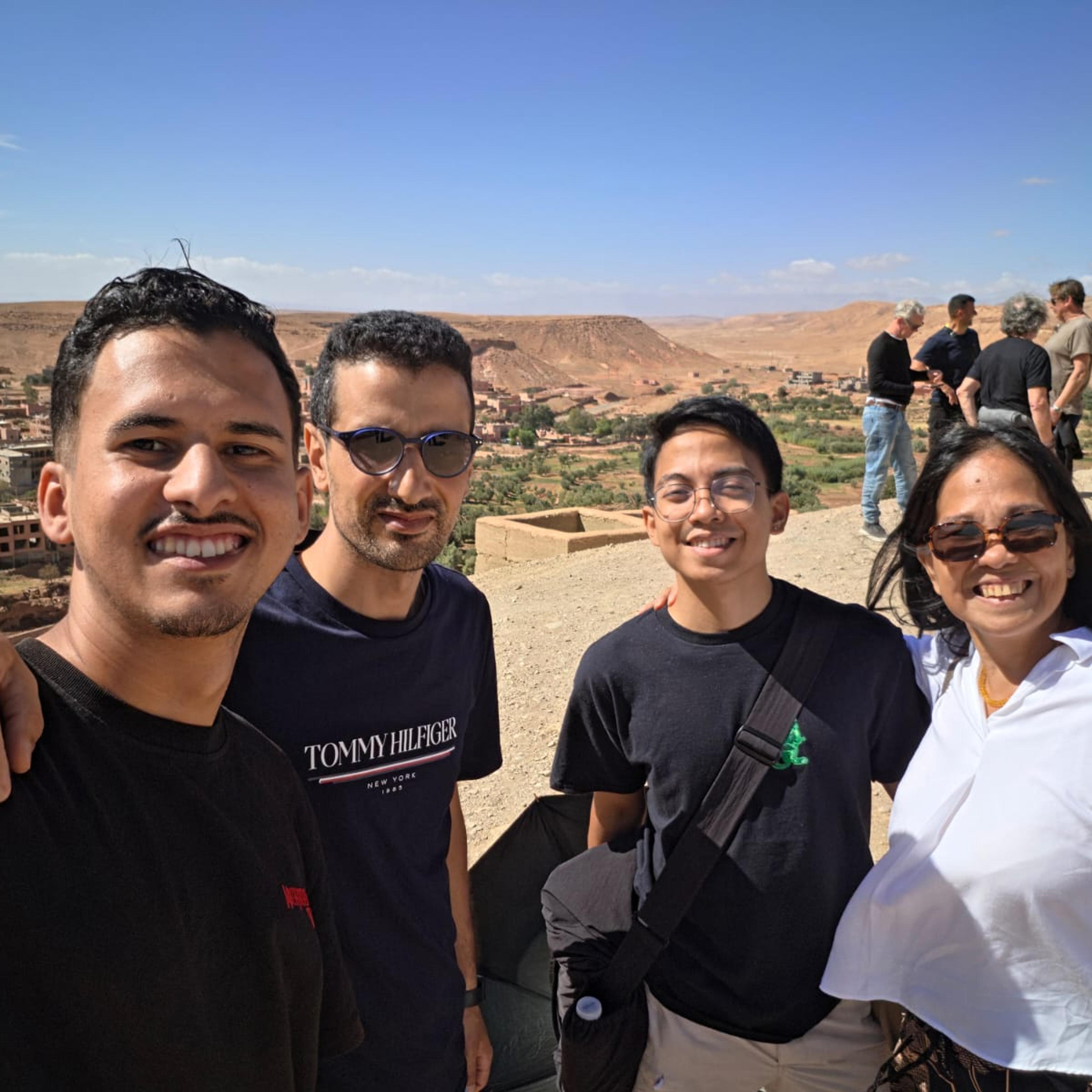 Moha and a colleague from AZA Morocco Tours with two guests at a viewpoint over a desert valley in southern Morocco