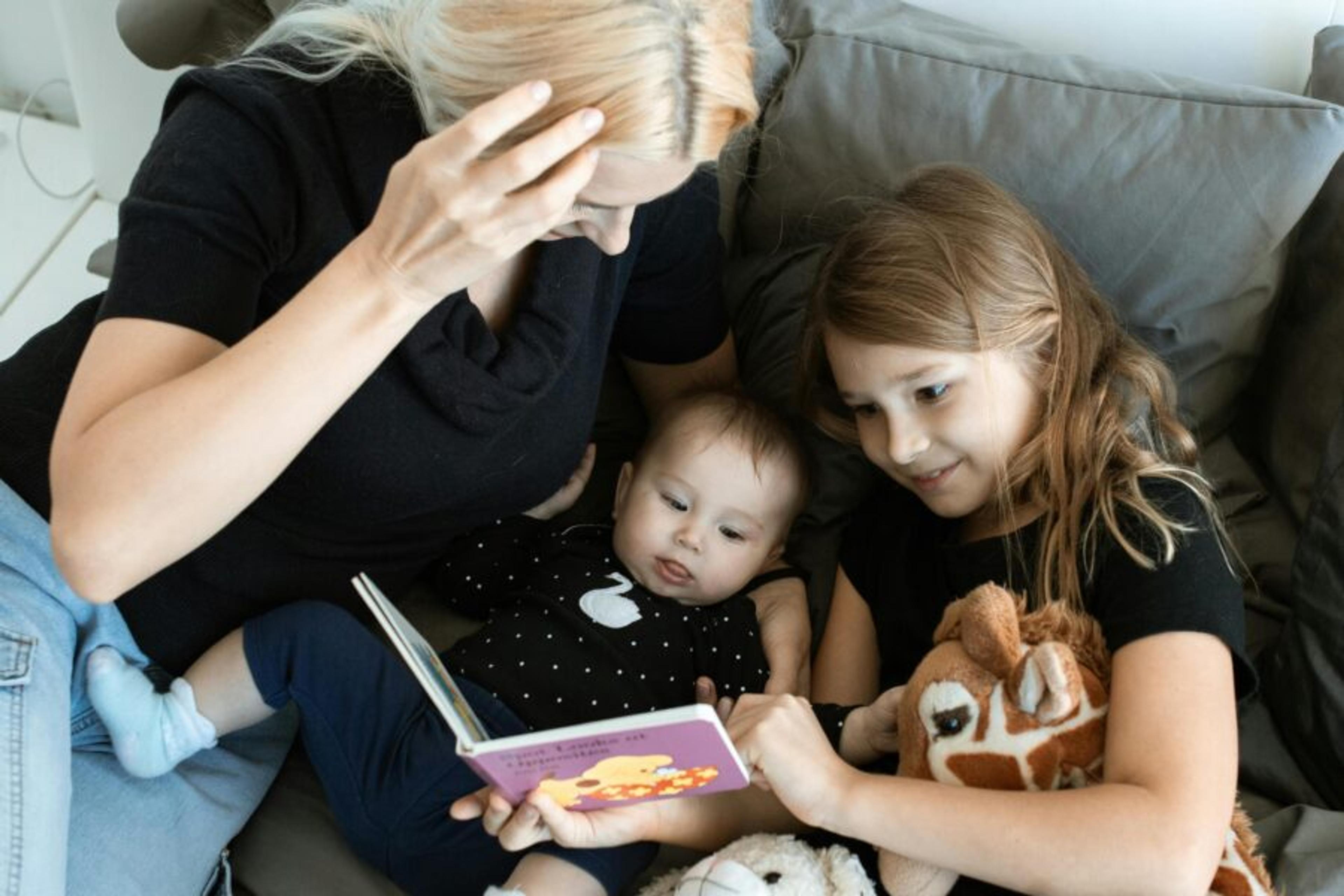 A mom who is a working parent laying in bed with her sick kids.