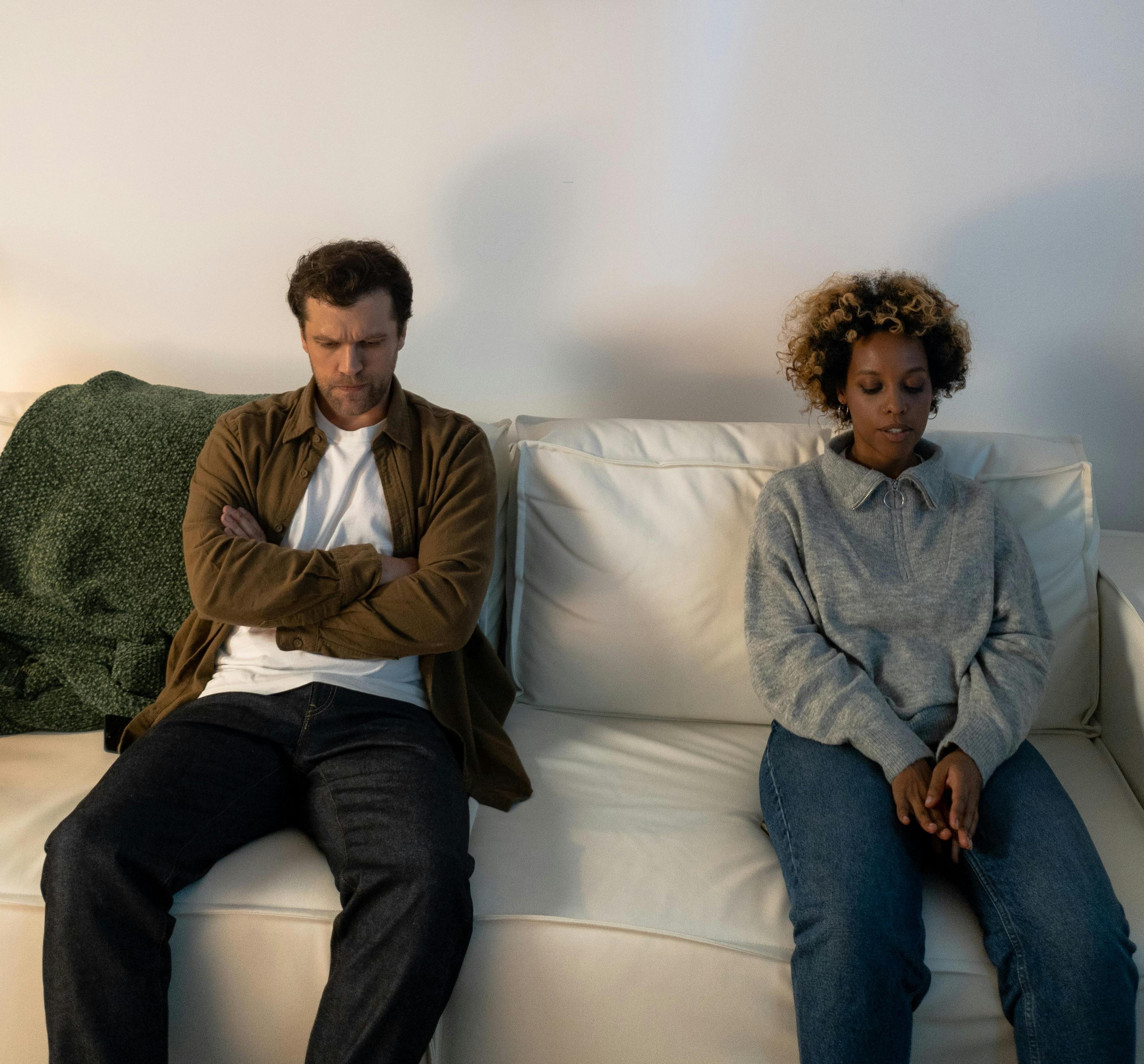 A man and woman sitting on a white couch and considering if there is a chance to get back together.