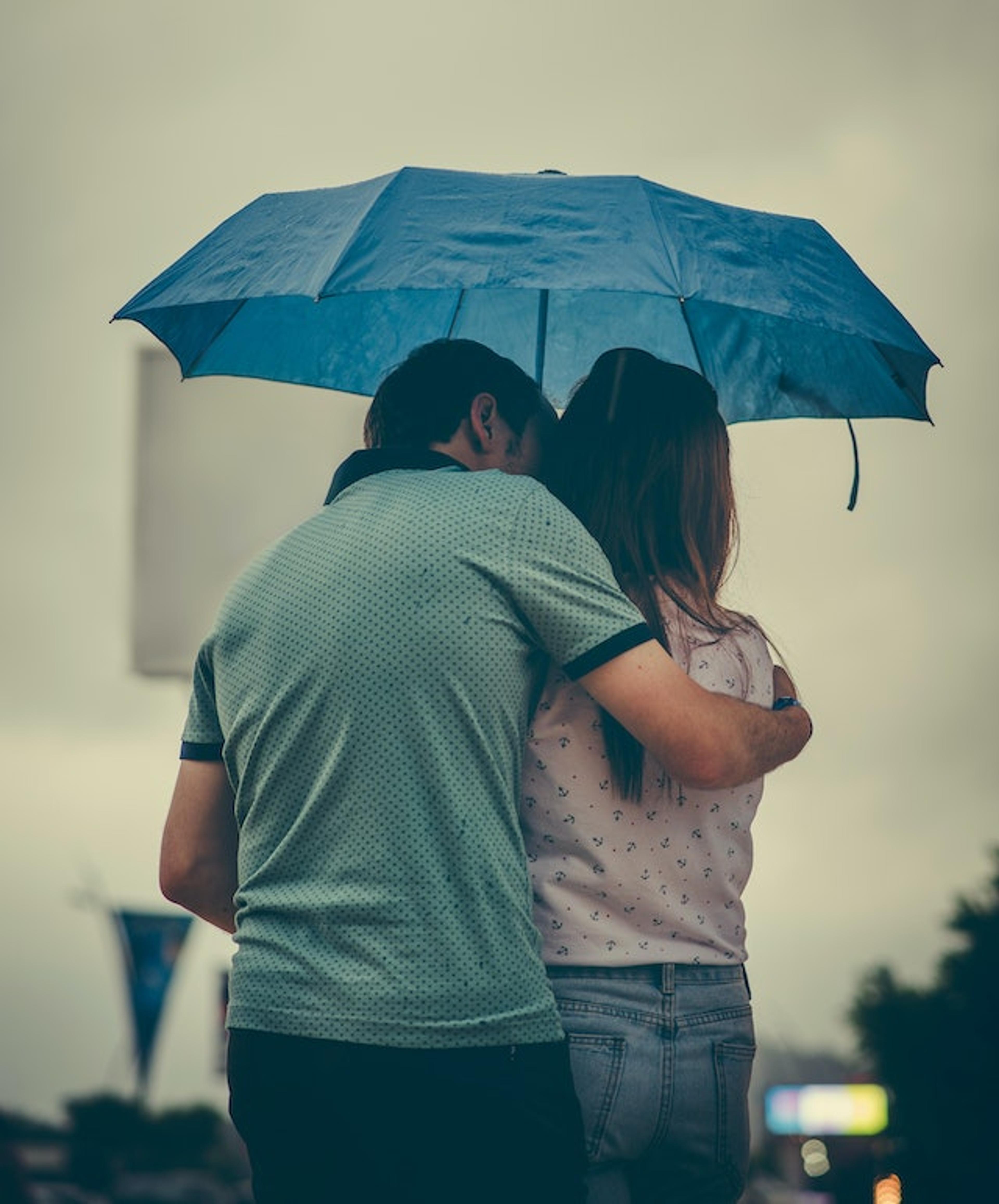 A couple standing under an umbrella, symbolising emotional sensitivities in relationship.