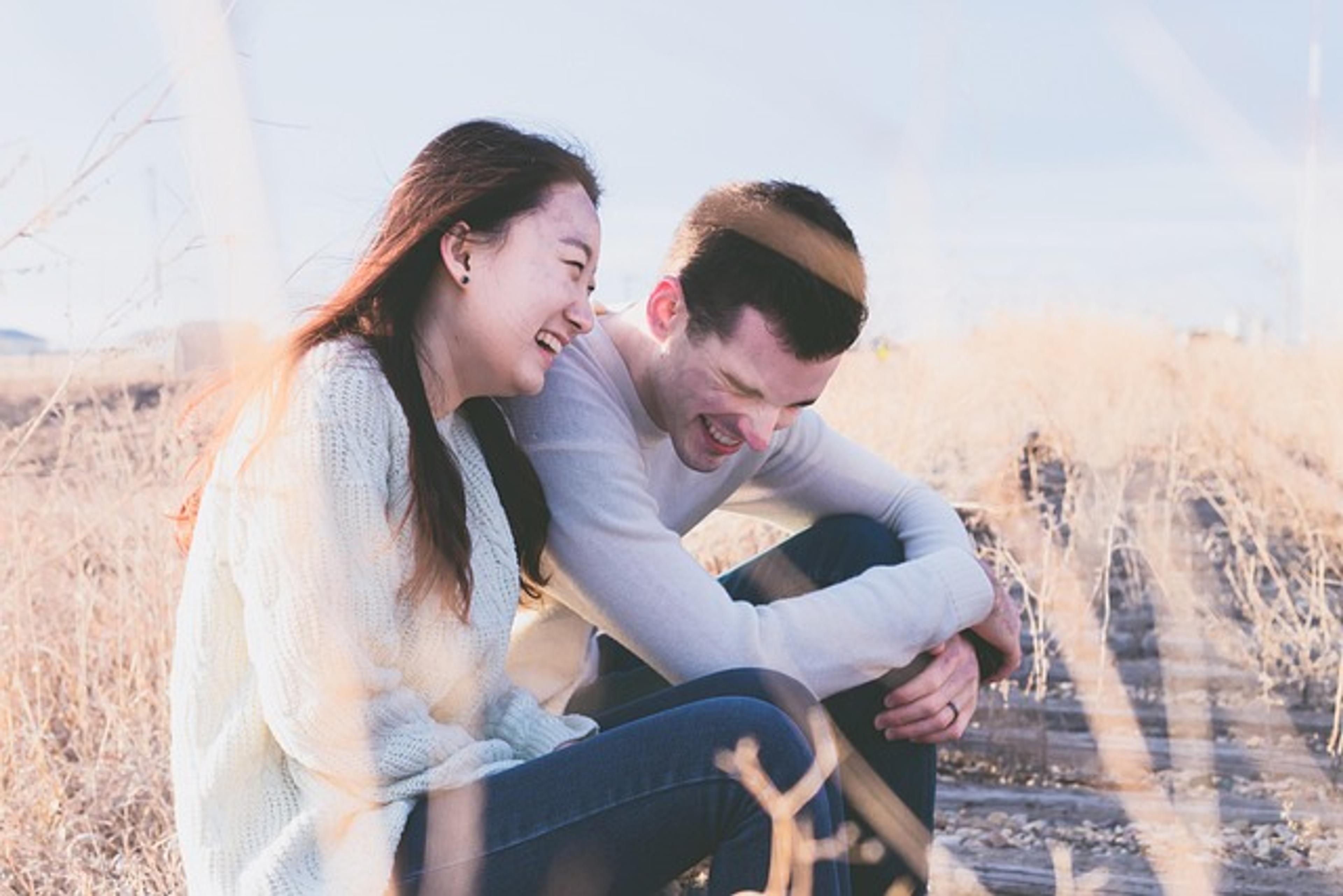 A man and a woman are sitting outside, laughing after they have used self guided couples therapy