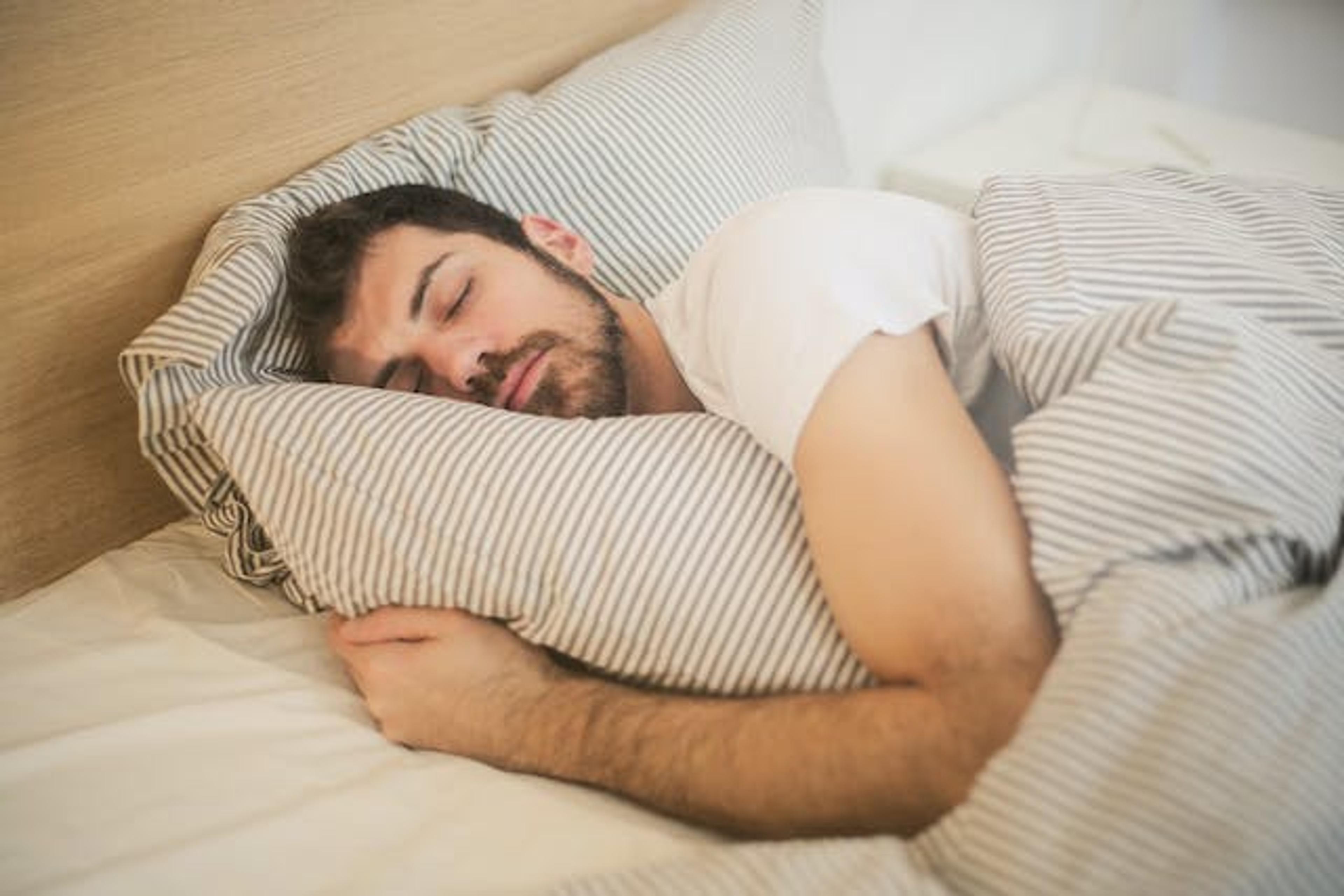 A man sleeping alone in his bed. He and his partner have a sleep divorce.