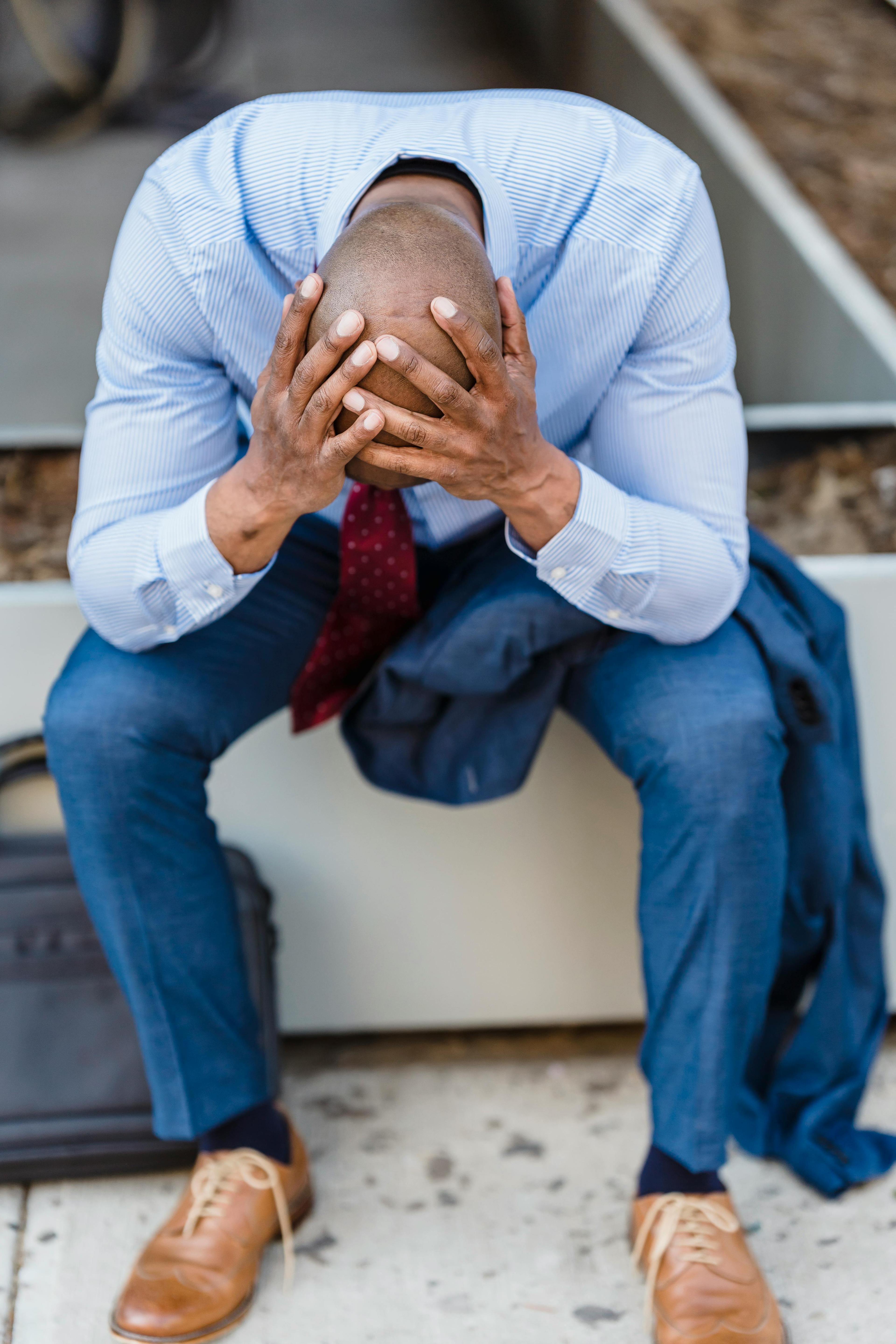 A man sitting on the ground and looks upset. Is he in a toxic relationship.