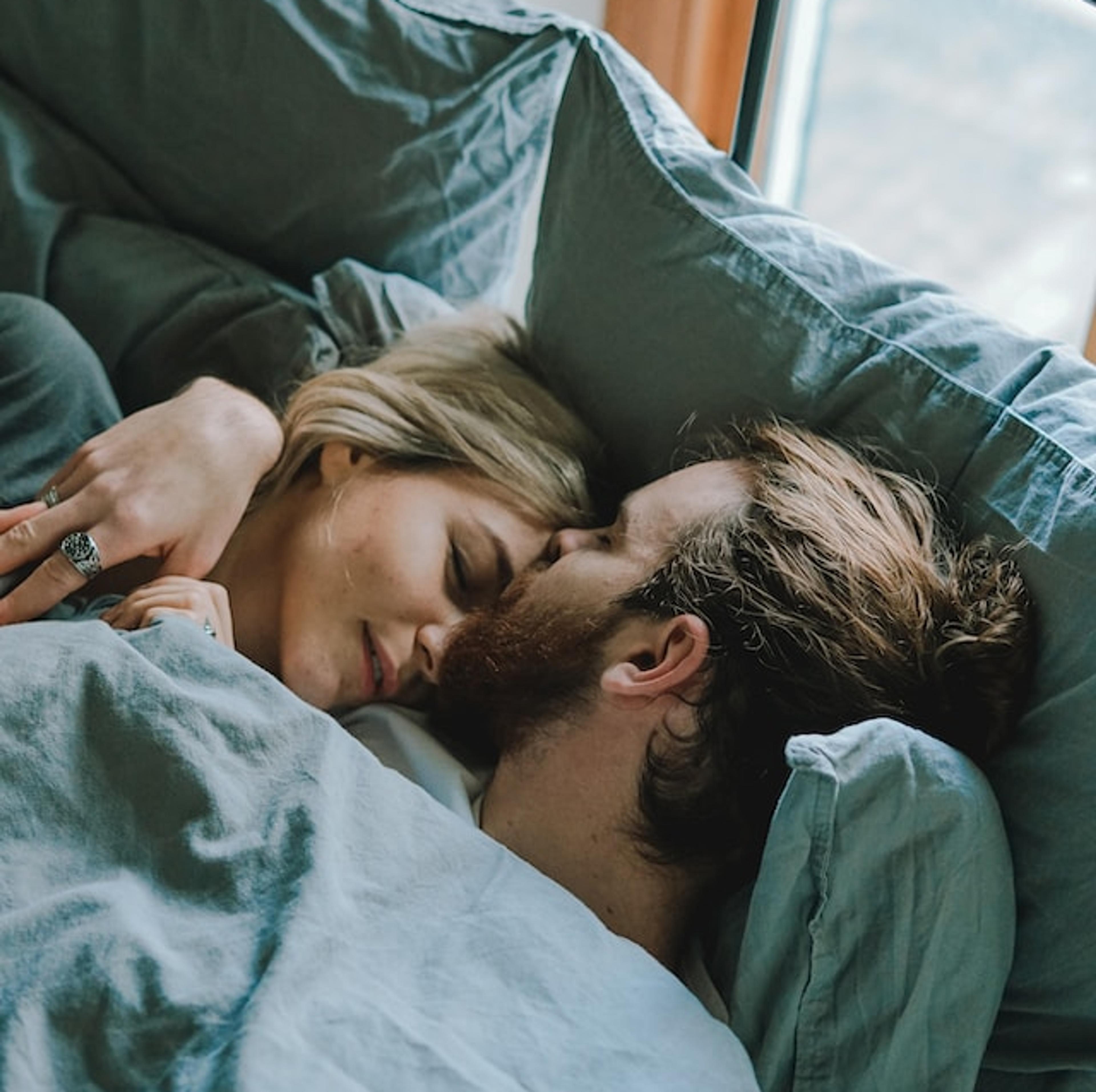 A man and a woman lying in bed kissing. They have differences in sexual desire.