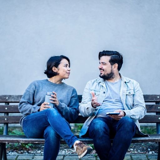 Due amiche sedute su una panchina del parco mentre parlano.