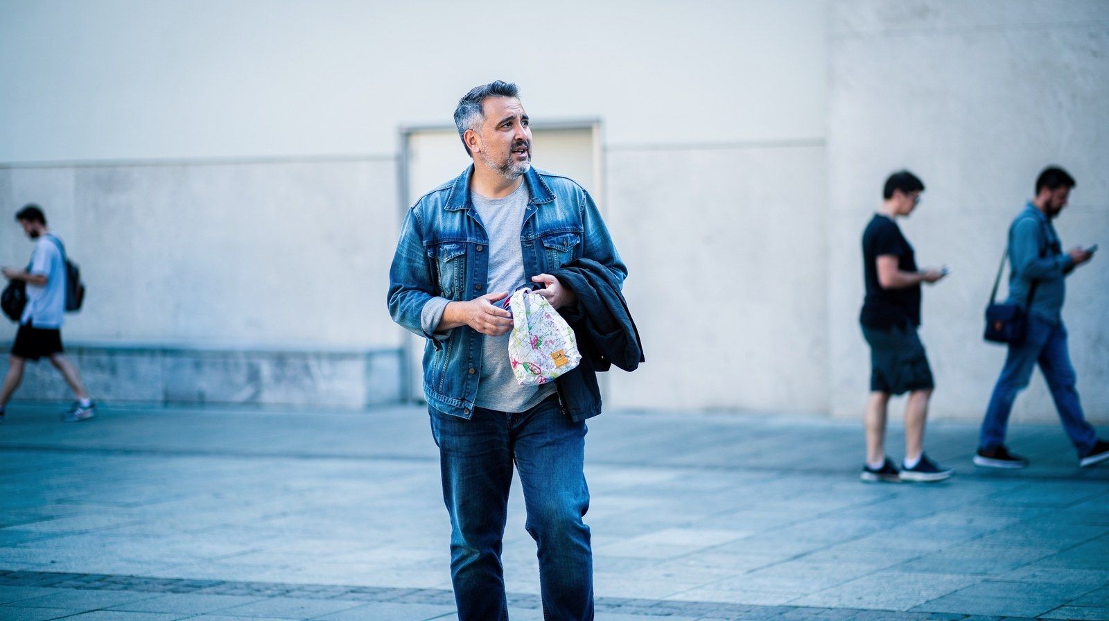 Un uomo si ferma sul marciapiede e si guarda intorno.