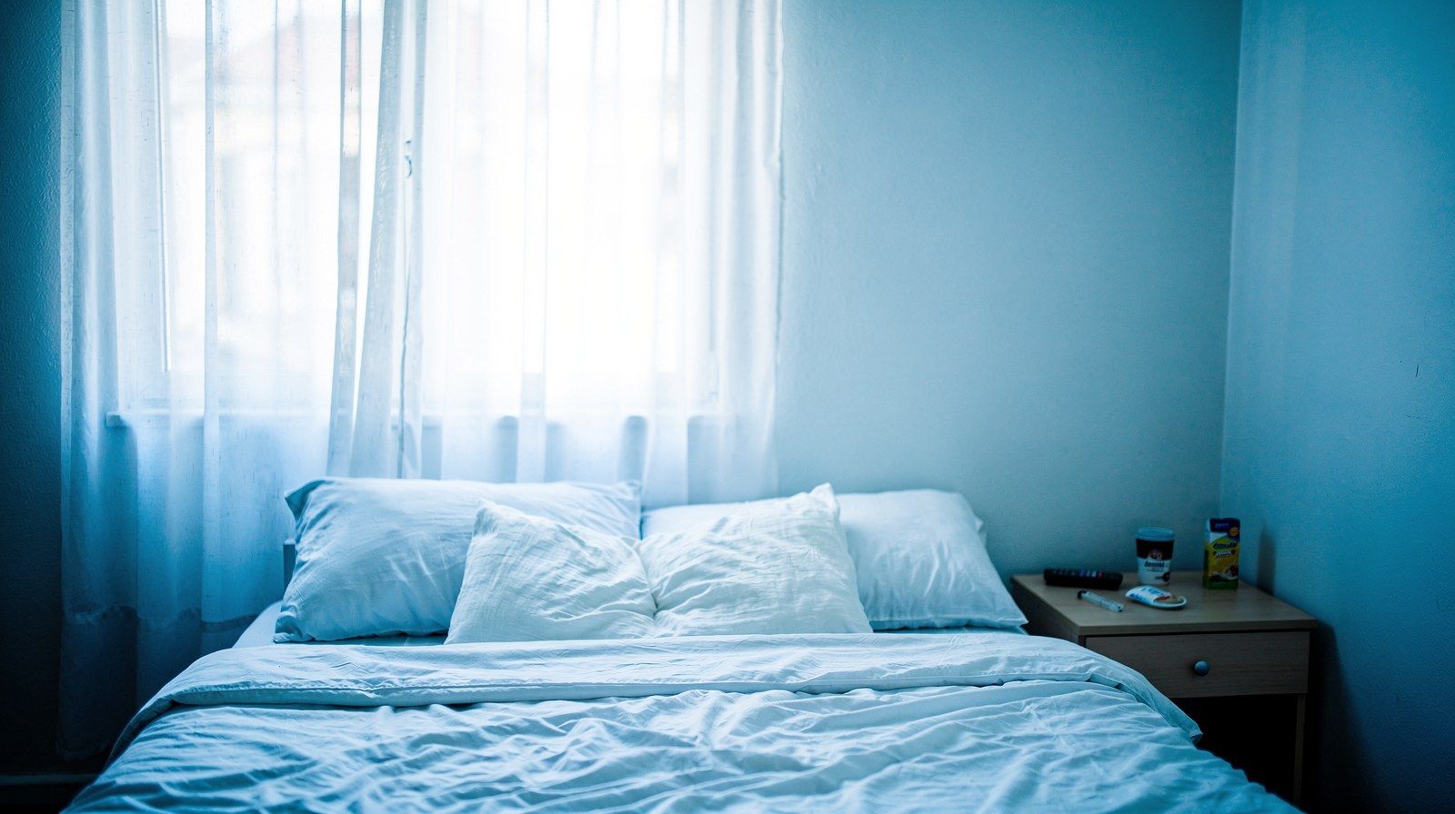 Un letto rifatto in una camera luminosa, con le tende aperte.