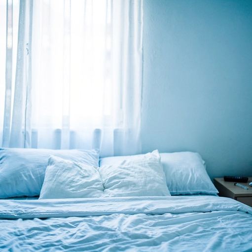 Un letto rifatto in una camera luminosa, con le tende aperte.