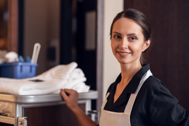 Smiling housekeeper next to a service cart with towels.